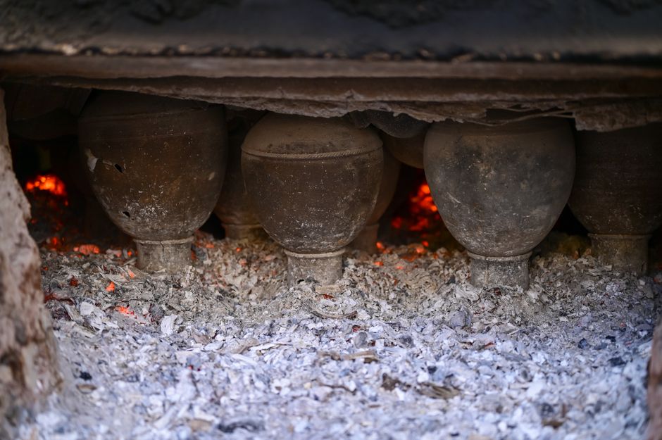 Clay pots firing in a traditional kiln in Hyderabad with glowing embers.
