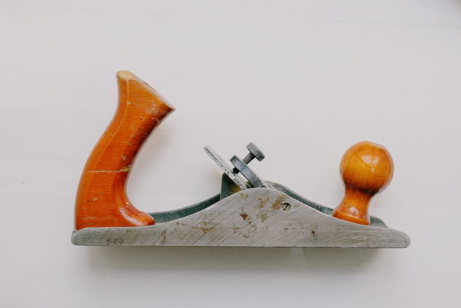 Top view of aged jack plane with wooden handle and bolt on metal lever cap on white background